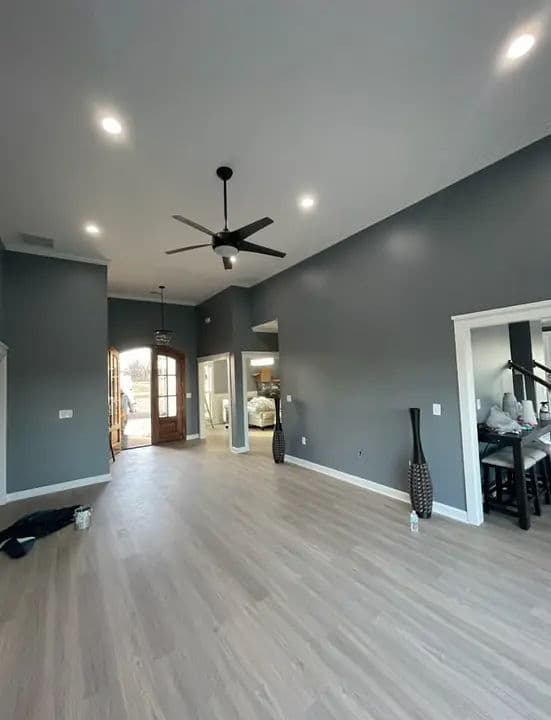 Spacious modern living room with gray walls, hardwood flooring, and ceiling fan.