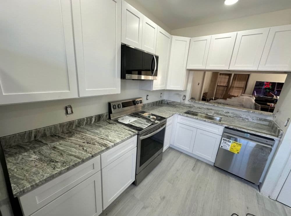 Modern kitchen with white cabinets, granite countertops, and stainless steel appliances.