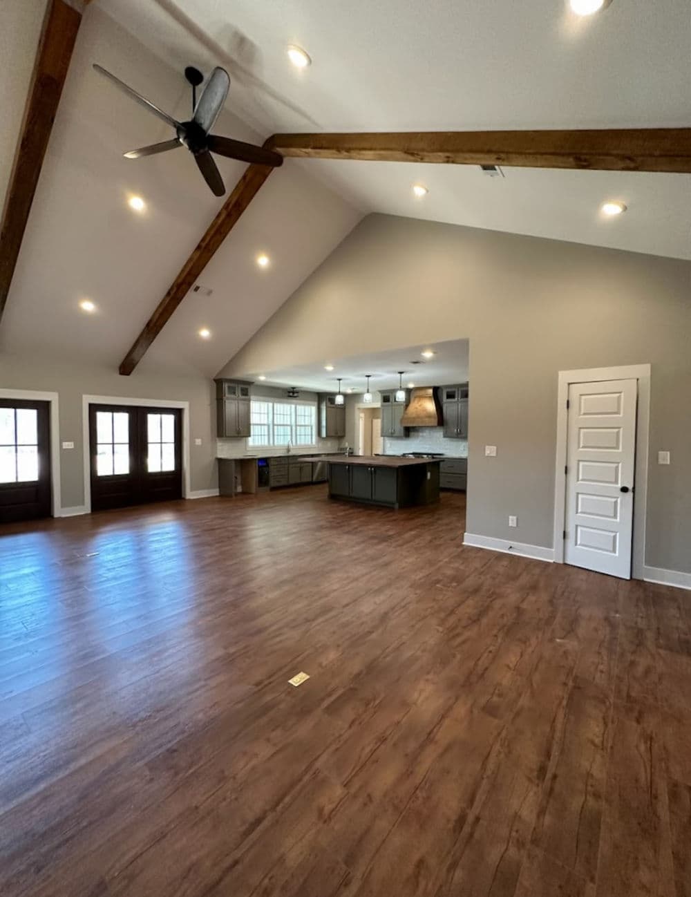 Spacious living room with vaulted ceiling, wooden beams, and modern kitchen view.
