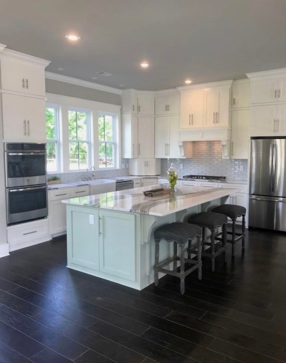 Modern kitchen with white cabinets, a large island, and stainless steel appliances.